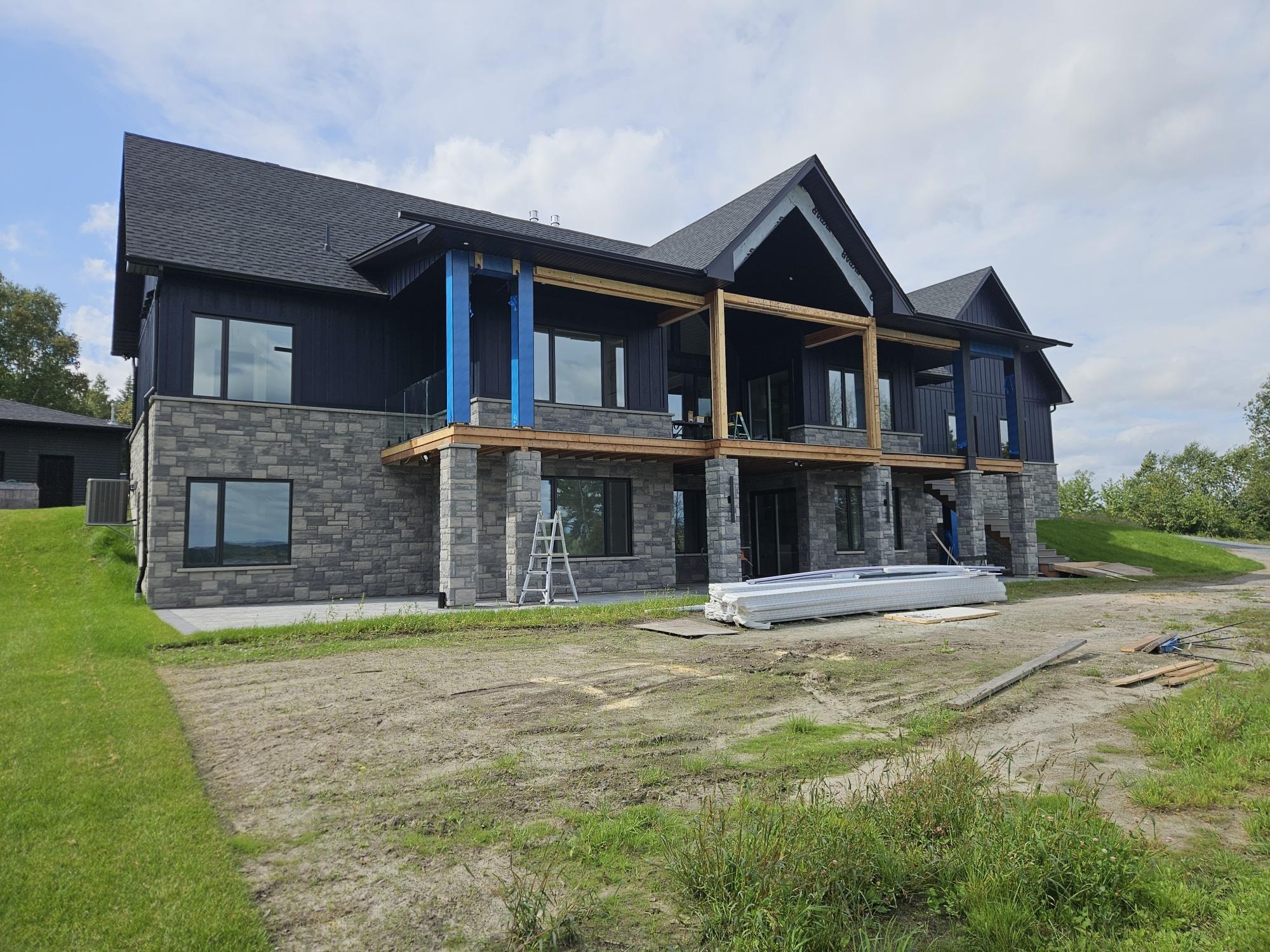 Wide view of dark home with full stone veneer lower storey, A1 Creative Masonry